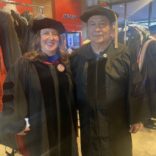 Man and woman standing in graduation regalia