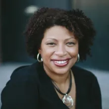 Woman wearing a black shirt and silver necklace and earrings, smiling