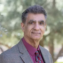 Man with suit jacket and purple shirt, standing outside