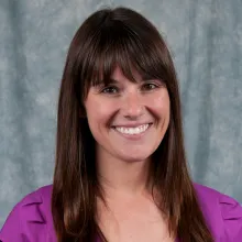 Woman with long brown hair and wearing a purple shirt