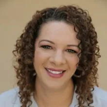 A woman with curly brown hair and a light blue blouse