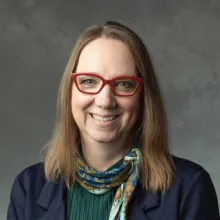 Woman wearing red glasses, green shirt and black jacket