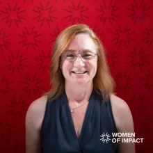 Woman with red hair sits in front of a red background