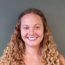 Woman with long blonde curly hair smiles for a photo