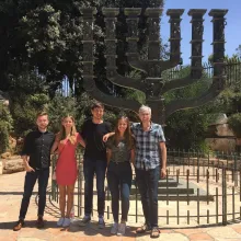 Professor and four students stand in front of a large Menorah, outside the Knesset in Jerusalem