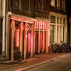 A street in Amsterdam at night, with red lights on in several doorways