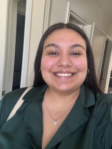 Woman with long brown hair and wearing a green blouse smiles for the camera