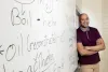 Corey Roberts against a white board with writing. 