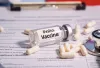 Photo of polio vaccine ampule, laying on top of paperwork, surrounded by pills and a stethoscope