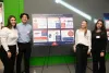 Four students stand around a presentation board titled "what drives employment success?"